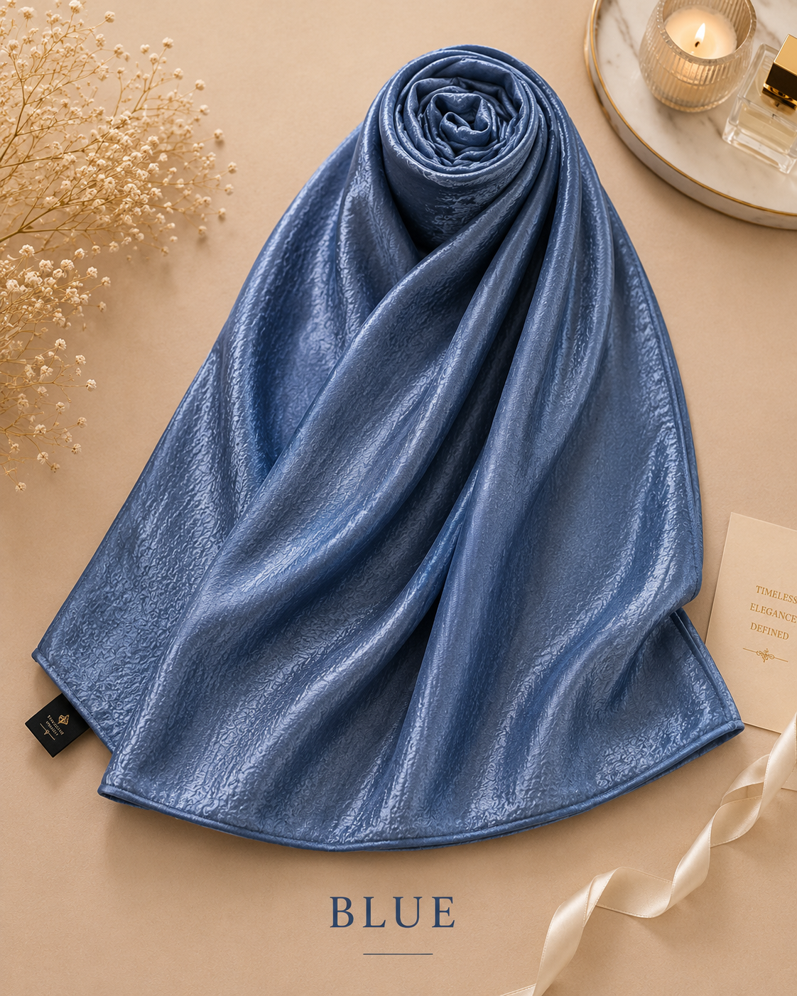 Rolled-up blue Bubble Satin Islamic Hijab Scarf on a beige surface with decorative elements