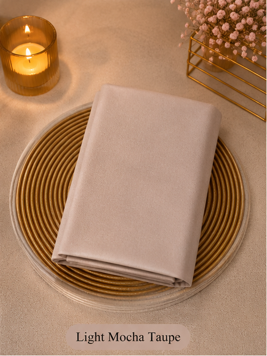Light Mocha Taupe Liquid Chiffon Hijab on a woven placemat with a candle and decorative elements.