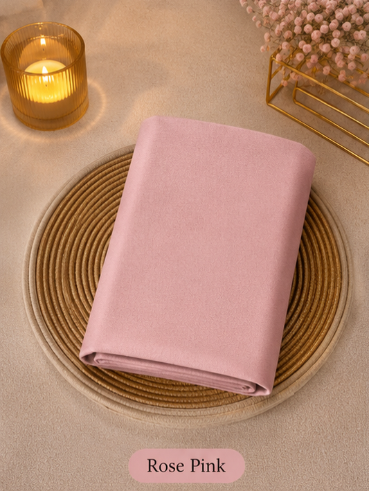 Rose pink Liquid chiffon Hijab fabric on a woven mat with a candle and flowers in the background