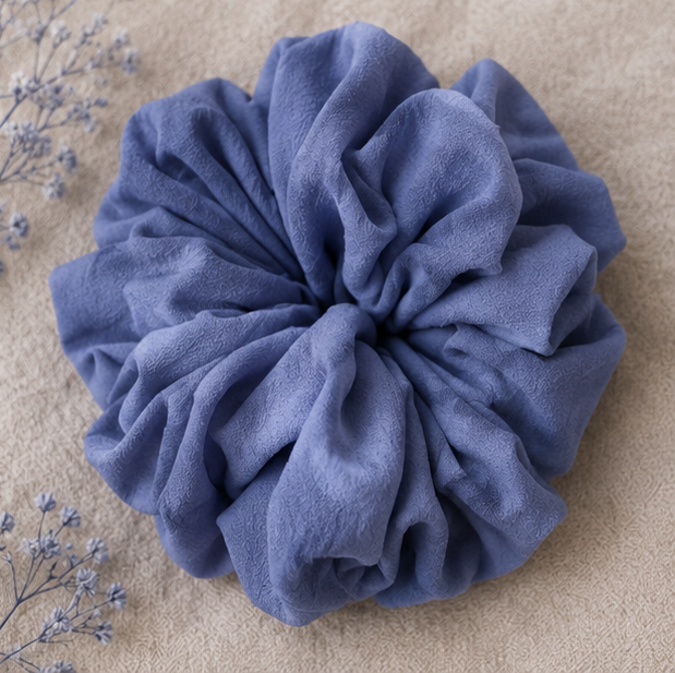 Blue scrunchie on a beige surface with dried flowers