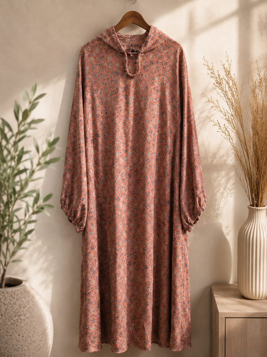 Peach Floral islamic premium namaz and prayer dress hanging on a wooden hanger against a neutral wall with decorative elements.