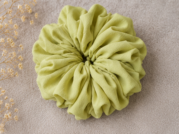 Green scrunchie on a beige background with dried flowers