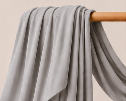 Silver Bamboo Jersey Islamic Hijab And Scarf fabric draped over a wooden rod against a beige background